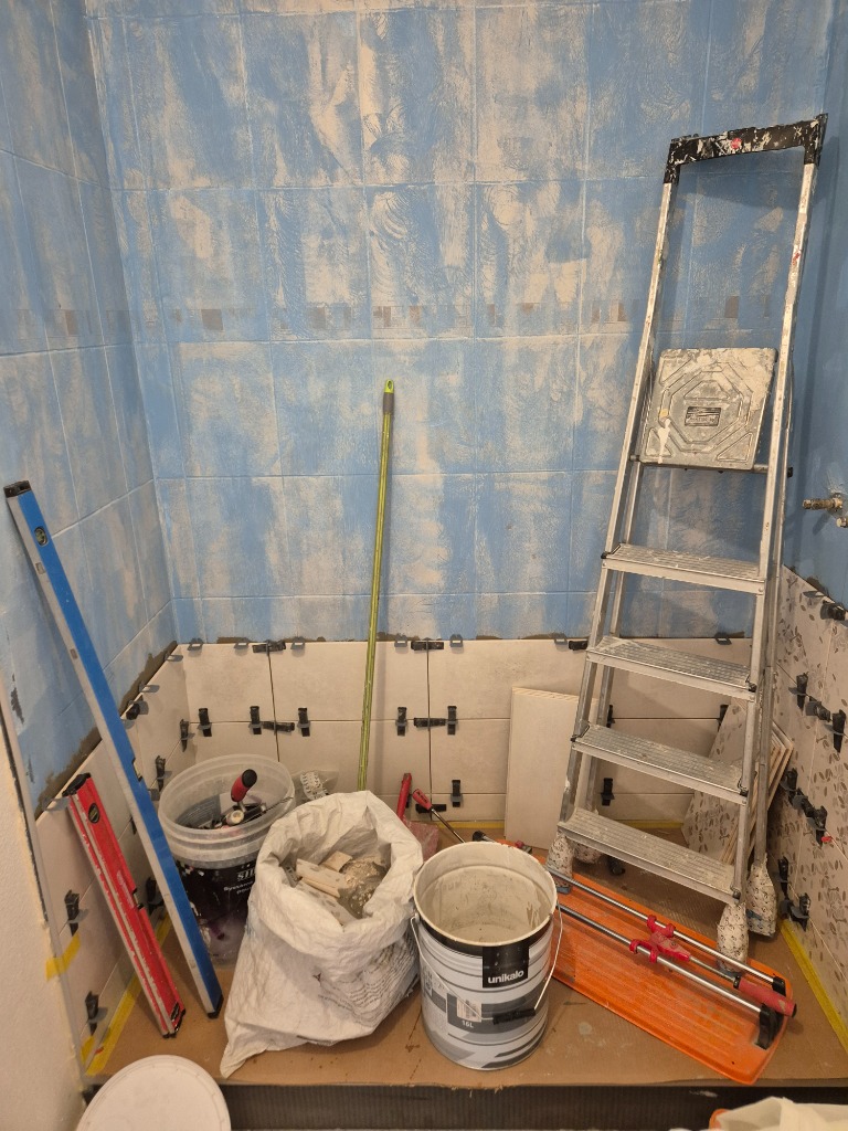 Chantier de salle de bain en cours de pose de carrelage bleu